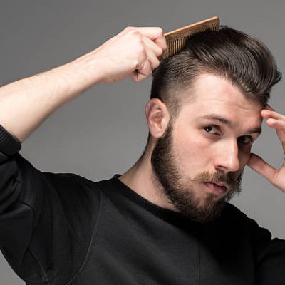 young man comb his hair on gray background
